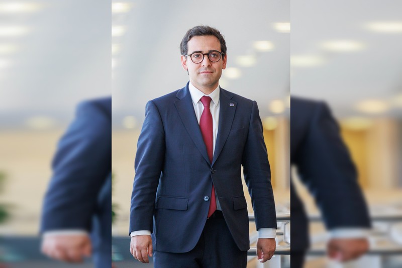 Stéphane Séjourné, European Commissioner for Prosperity and Industrial Strategy, in an official portrait wearing a navy suit and red tie with an EU lapel pin.