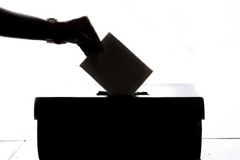 Silhouette of a hand casting a ballot into a ballot box