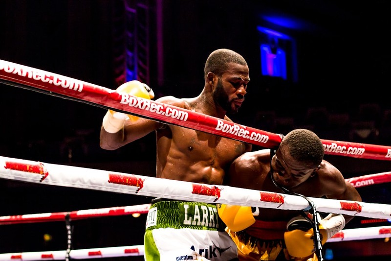 Two boxers compete in a professional boxing match under arena lights