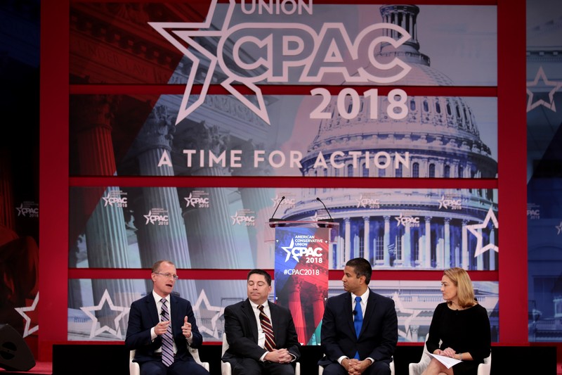 FCC officials seated on a panel at CPAC 2018 with a patriotic stage backdrop featuring the U.S. Capitol