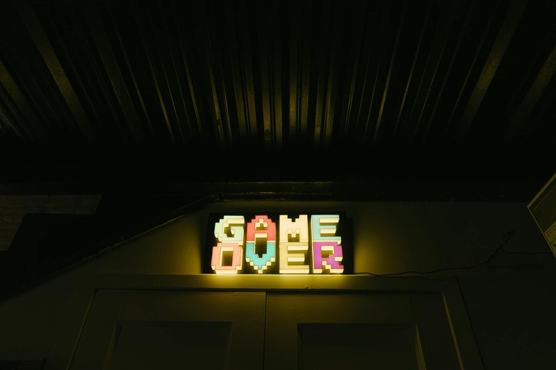 A glowing neon Game Over sign in a dark arcade setting