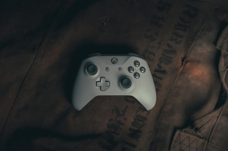 A white Xbox controller resting on textured brown fabric, highlighting its buttons and design.