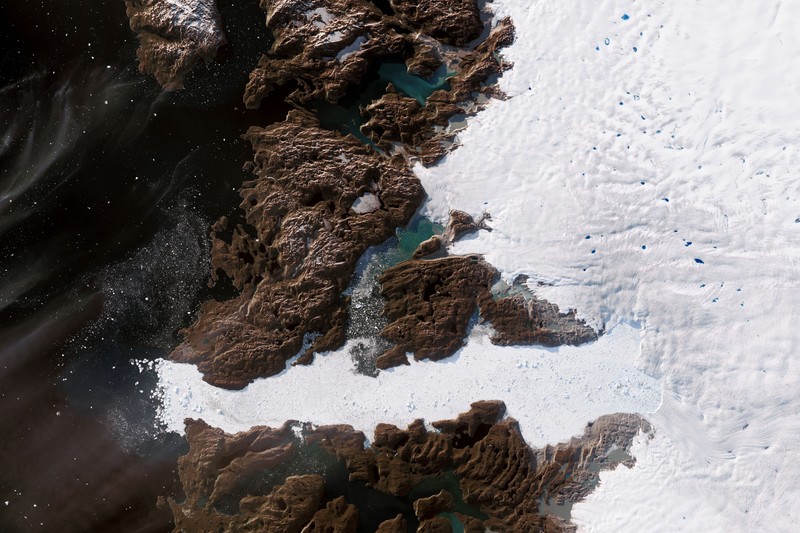 Satellite view of Jakobshavn Glacier in western Greenland showing ice, exposed rock, and meltwater pools