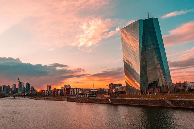 The European Central Bank tower in Frankfurt at sunset, reflected in the Main River