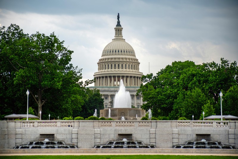 The United States Capitol building viewed from the National Mall on an overcast day, with a fountain in the foreground