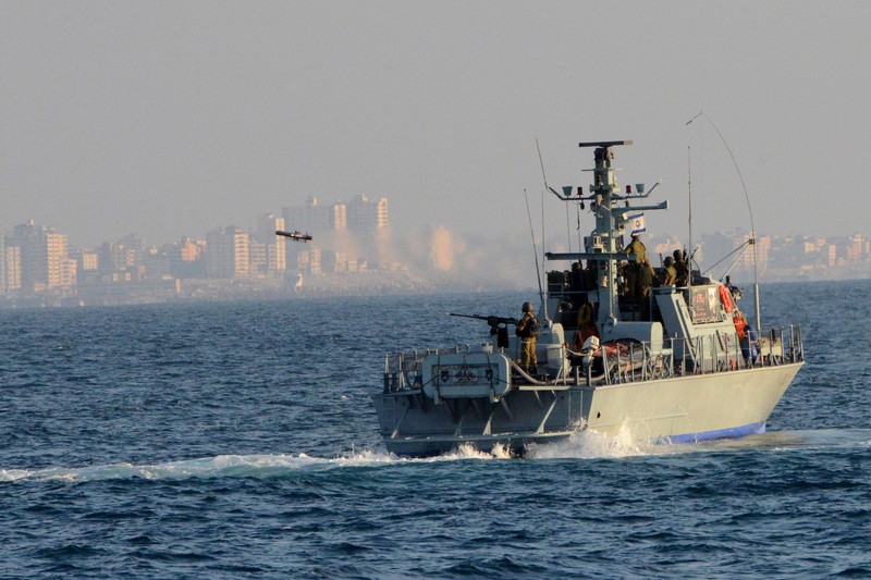 An Israeli Navy Shaldag-class patrol boat cruises through Mediterranean waters near a coastal city skyline