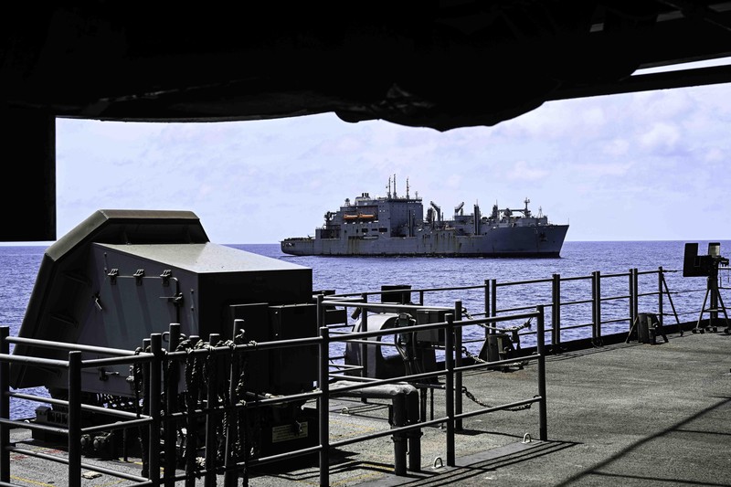A U.S. Navy supply ship approaches an aircraft carrier during replenishment-at-sea operations in the Indian Ocean
