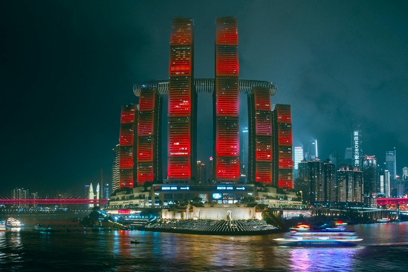 Neon-red illuminated skyscrapers reflecting in a river at night, creating a cyberpunk cityscape