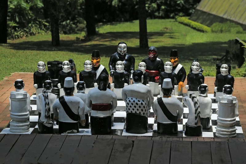 Unique artistic chess set with stylized pieces on an outdoor board in a park setting