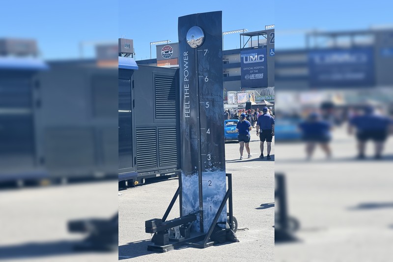 A High Striker carnival strength-testing game at Las Vegas Motor Speedway, with a vertical numbered scale and a bell target at the top