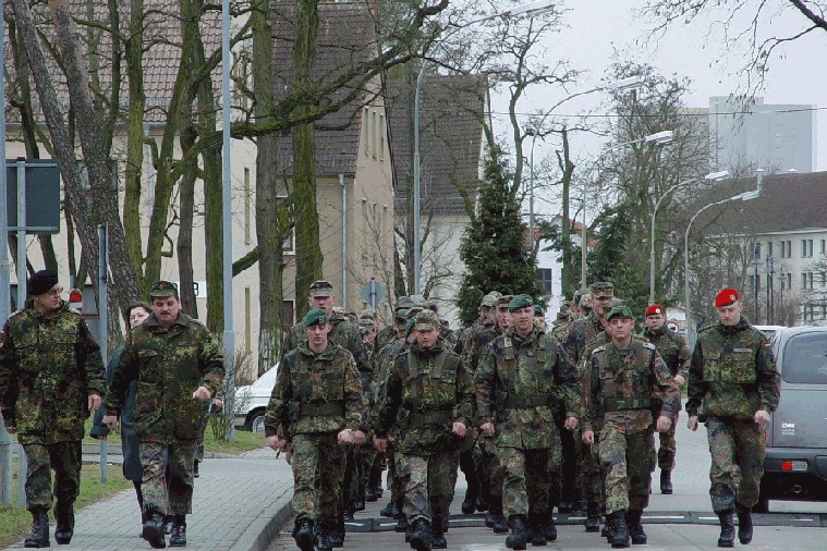 Bundeswehr soldiers in camouflage uniforms marching in formation through an urban street