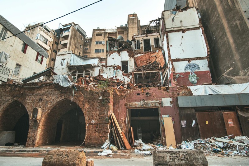 Heavily damaged buildings with collapsed walls and rubble in a dense urban area of Beirut