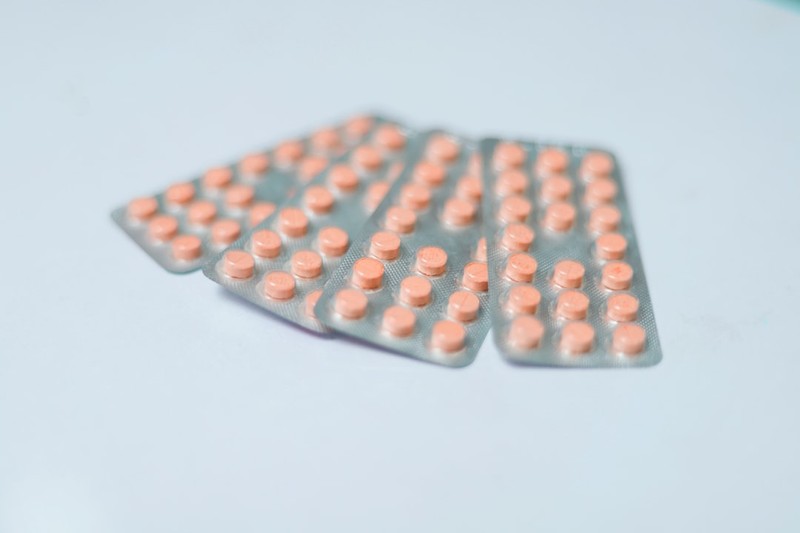 Blister packs containing round orange pills arranged on a light surface