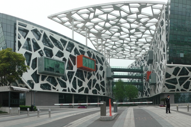 The Alibaba Group headquarters building in Hangzhou, China, featuring a distinctive white geometric lattice facade with colorful glass modules