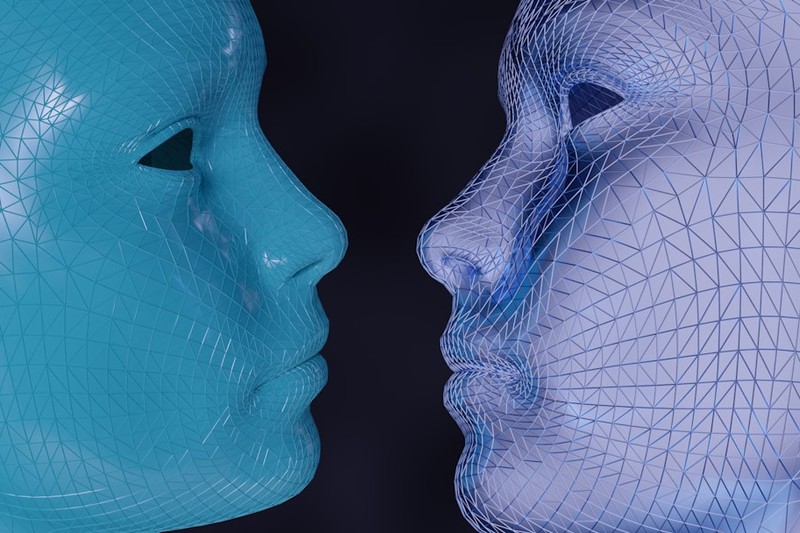 A solid teal face and a wireframe digital face nearly touching, symbolizing real versus AI-generated identity