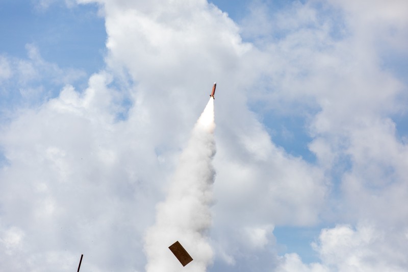 A PAC-2 Patriot interceptor missile launches during a live-fire exercise, leaving a thick white smoke trail against a partly cloudy sky.