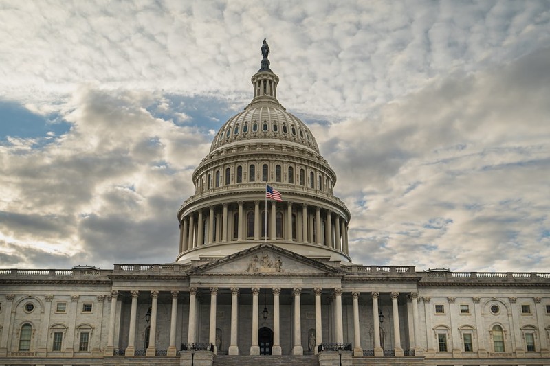 The dome of the US Capitol building under a cloudy sky