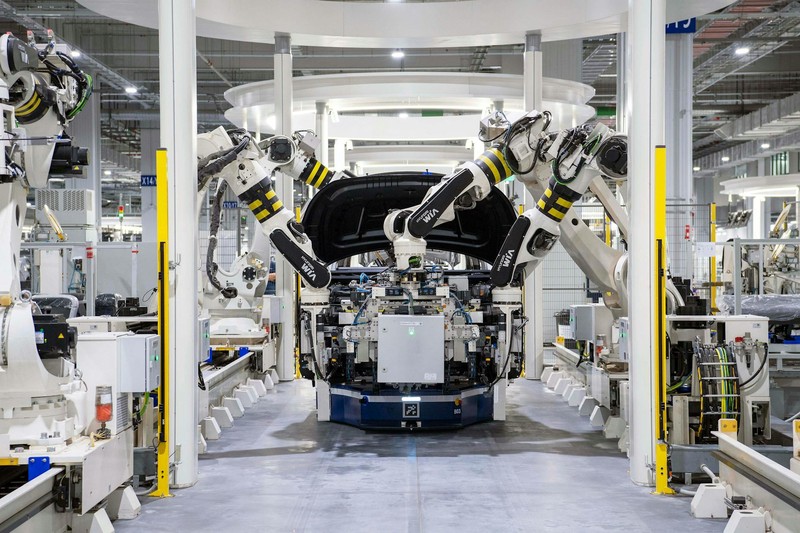 Robotic arms assembling a car body on a modern automotive factory production line