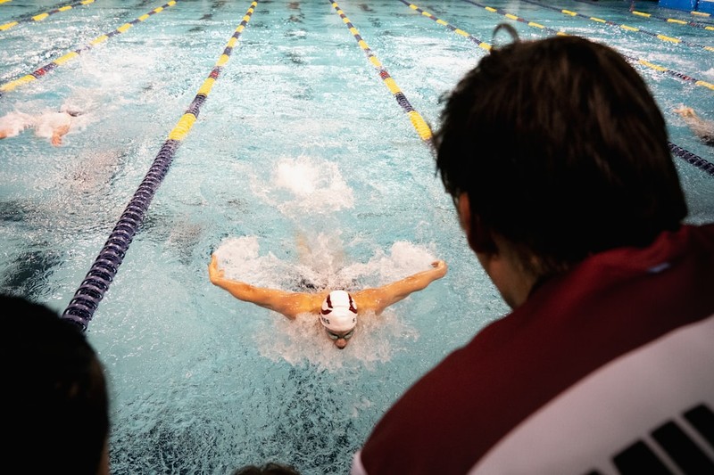 A competitive swimmer performing the butterfly stroke in a multi-lane pool during a race