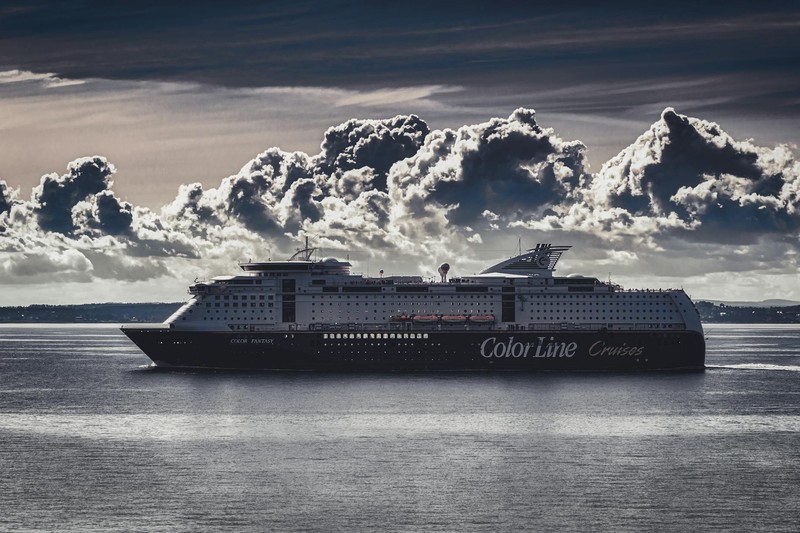 A large cruise ship sailing through the open ocean under dramatic storm clouds