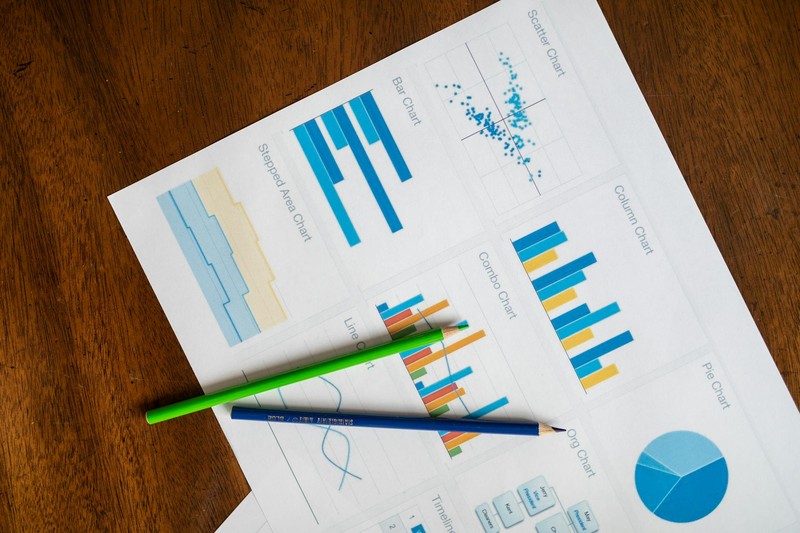 Colorful data charts and graphs spread across a wooden desk surface