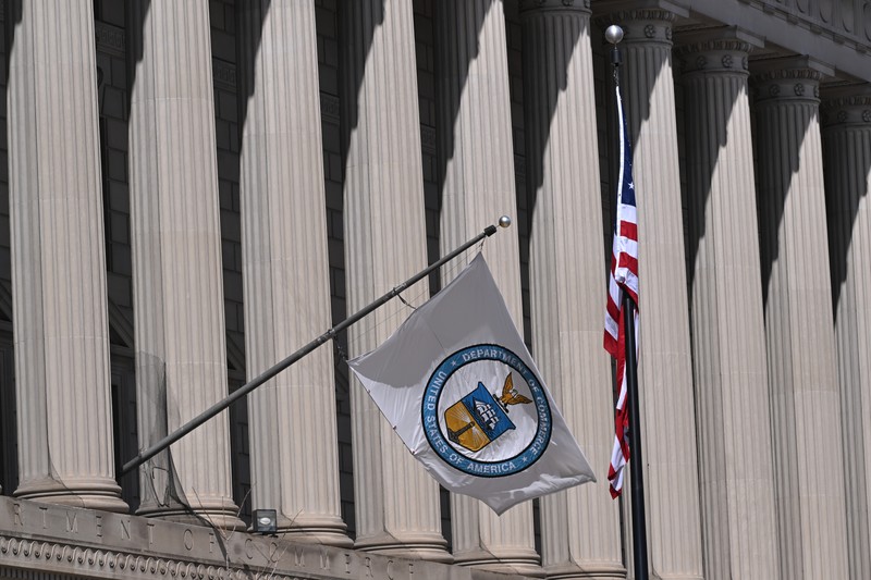 The U.S. Department of Commerce flag and American flag flying outside the Herbert C. Hoover Building in Washington, D.C.