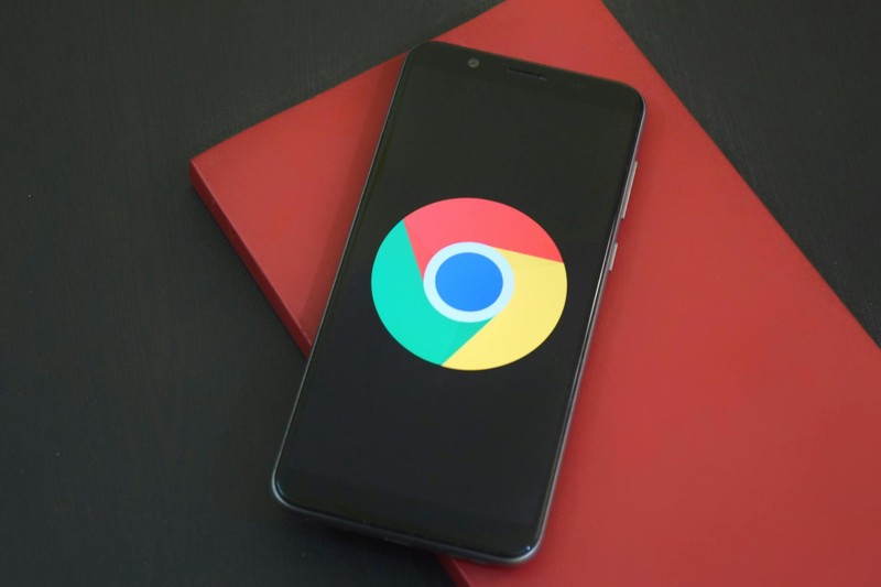 A smartphone displaying the Google Chrome logo resting on a red notebook
