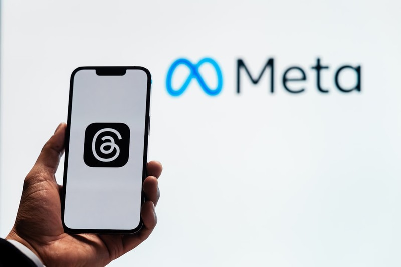 A hand holds a smartphone with the Meta logo displayed in the background