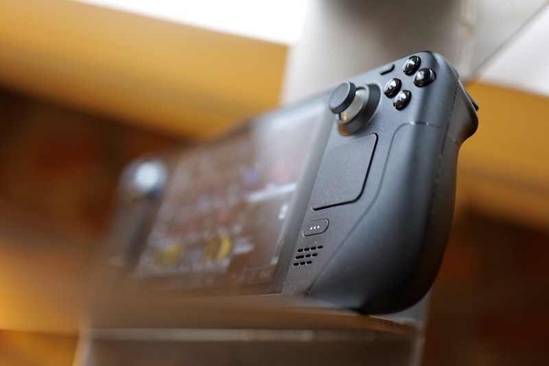 Close-up of a black video game controller with analog stick and buttons in soft focus