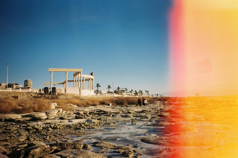 A pavilion and buildings stand on dry, rocky ground far from the receding Caspian Sea shoreline in Aktau, Kazakhstan