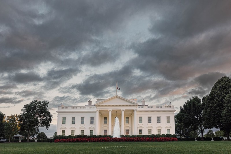 The White House under a dramatic overcast sky at sunset