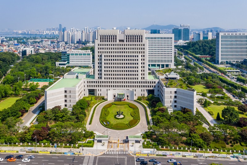 Aerial view of the Supreme Court of Korea building in Seoul surrounded by trees with the city skyline in the background