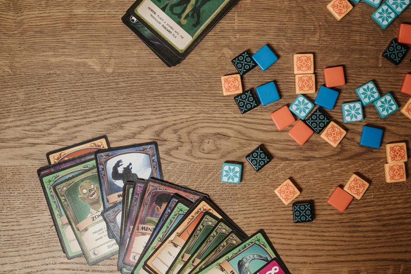 Colorful tabletop game cards and tiles spread across a wooden table