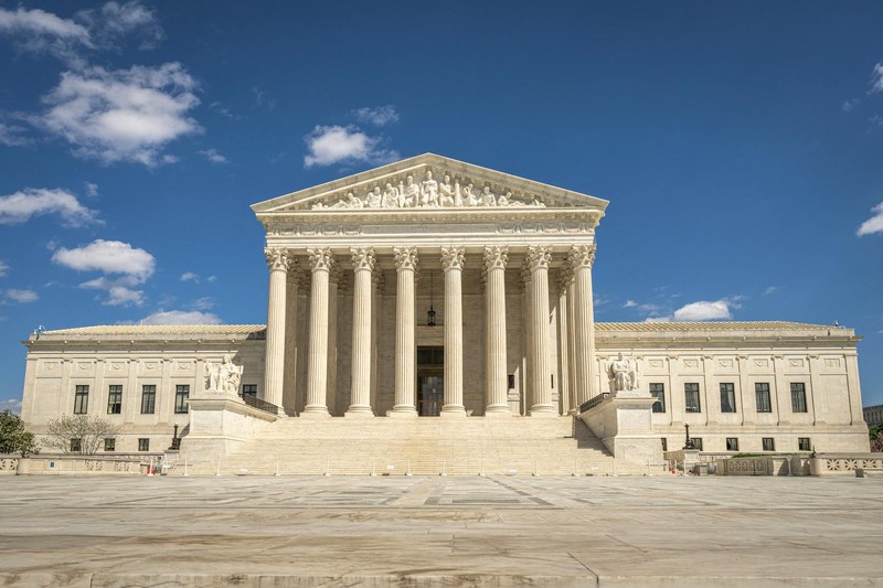 The United States Supreme Court building facade under a clear blue sky