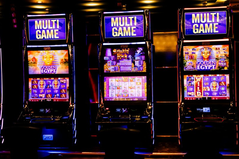 Three illuminated multi-game slot machines in a dimly lit casino