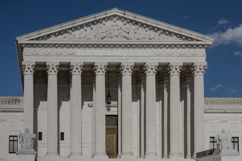 The United States Supreme Court building in Washington, D.C., viewed from the front under a clear blue sky