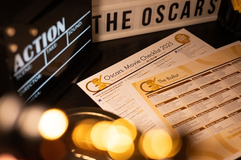 A film clapperboard and Oscars sign with warm bokeh lights in the background