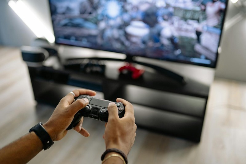 Hands holding a gaming controller while playing a video game on a TV
