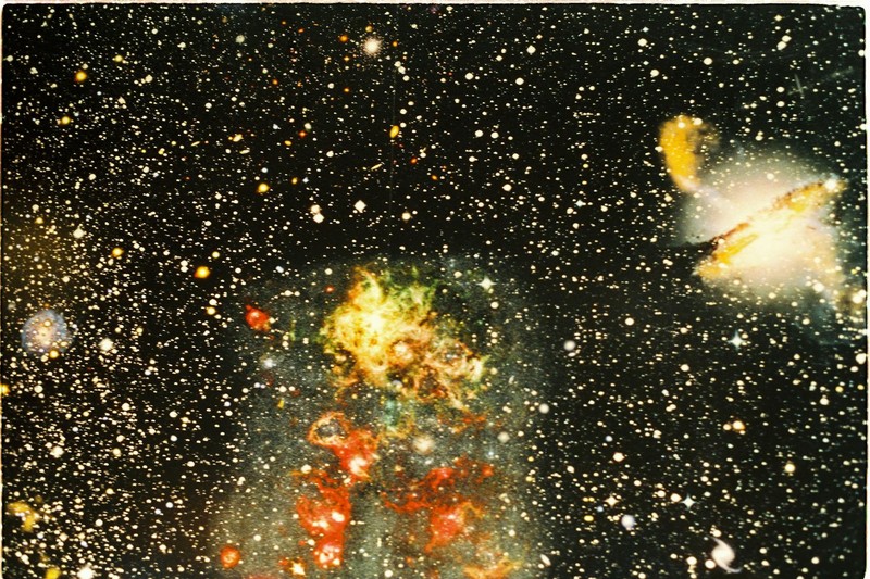 A distant galaxy and colorful nebula set against a dense star field in deep space