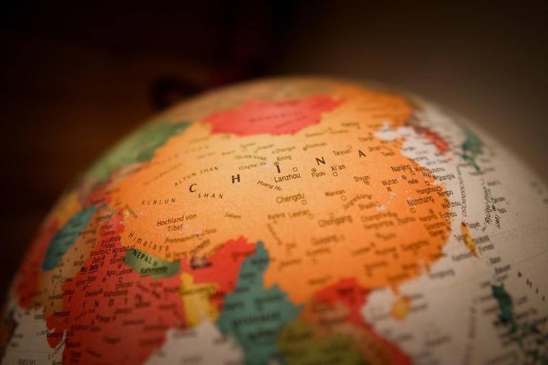 A globe close-up highlighting China with warm lighting and blurred background