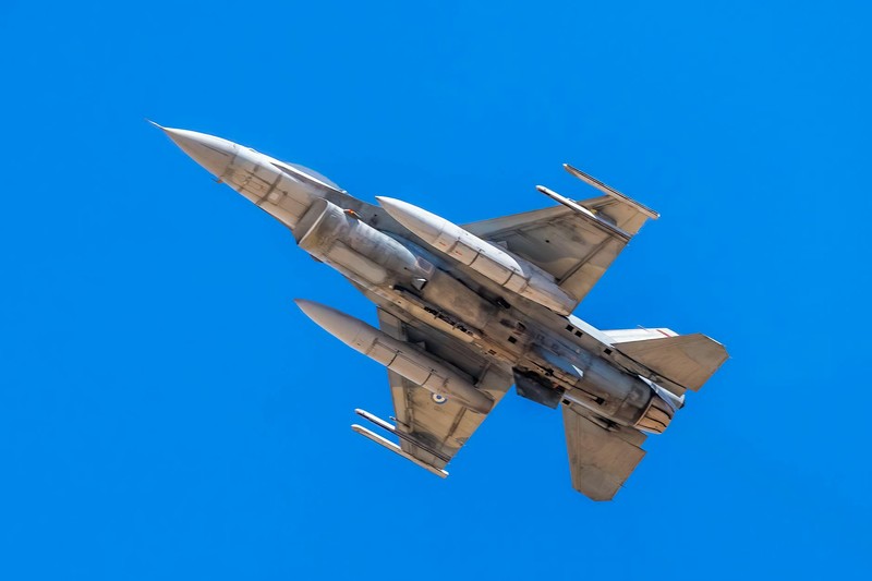 An F-16 fighter jet in flight against a clear blue sky
