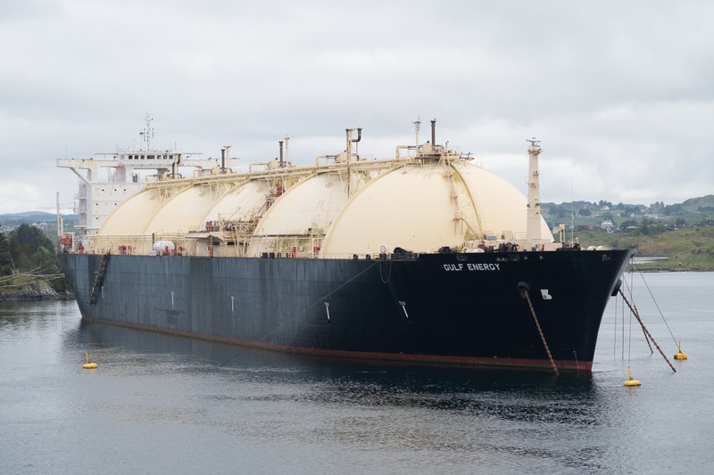 An LNG tanker with spherical storage tanks anchored in a coastal waterway