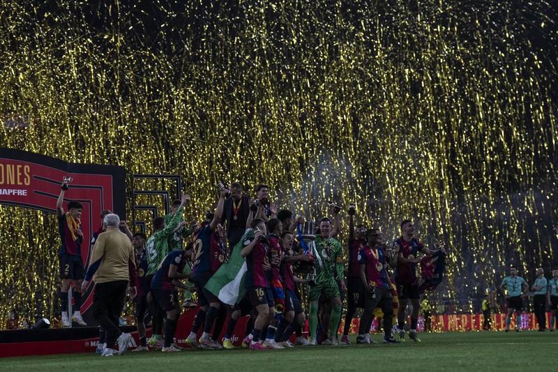 Barcelona players celebrate with a trophy on stage as golden confetti rains down
