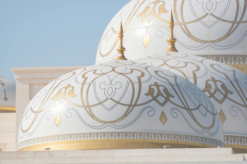 Ornate white and gold domes of Qasr Al Watan, the UAE Presidential Palace in Abu Dhabi, against a clear blue sky
