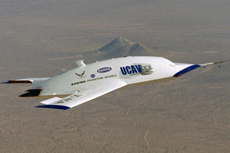 A Boeing X-45A unmanned combat aerial vehicle flying over desert terrain