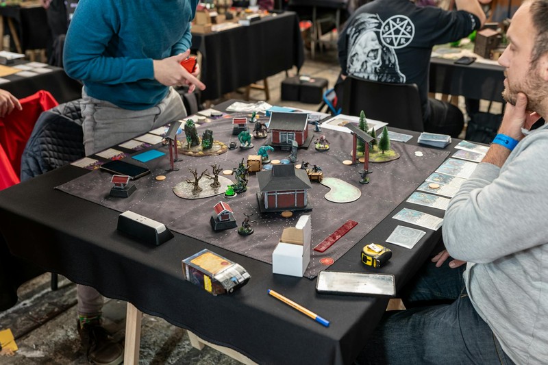 Players engaged in a tabletop miniature wargame at a gaming tournament