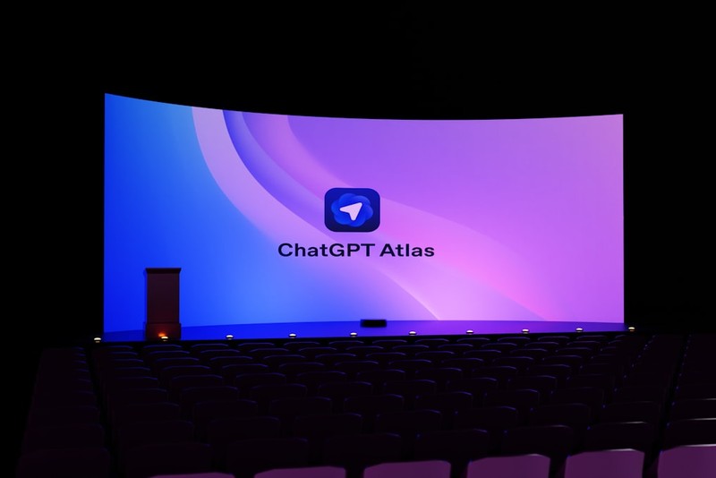 ChatGPT Atlas logo displayed on a large screen in a dark auditorium with empty theater seats