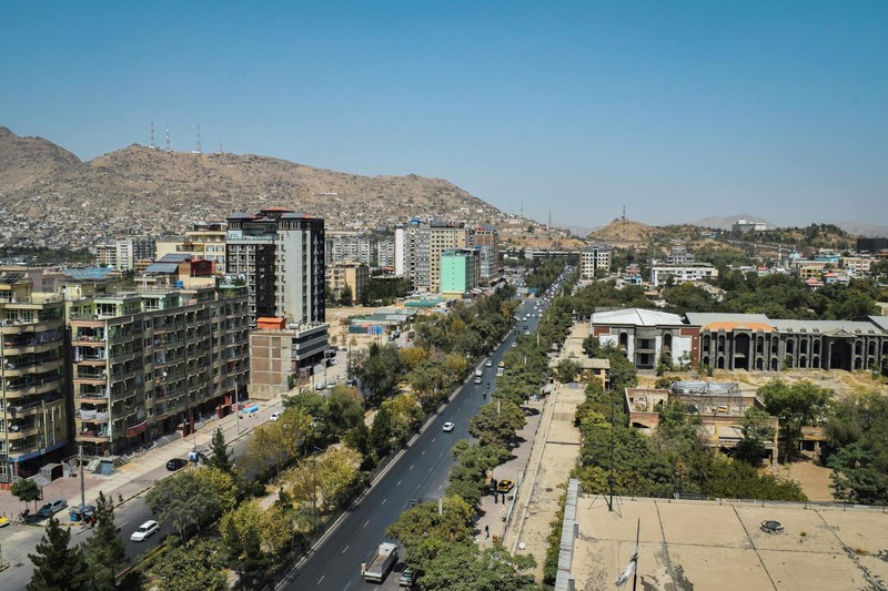 Aerial view of Kabul, Afghanistan, with urban buildings, a central road, and mountains in the background