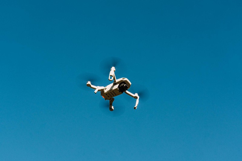 A drone flying against a clear blue daytime sky