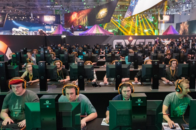 Blizzard's Overwatch gaming booth at Gamescom with rows of players at branded gaming stations